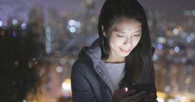 Geceleri şehri cep telefonu kullanan kadın 