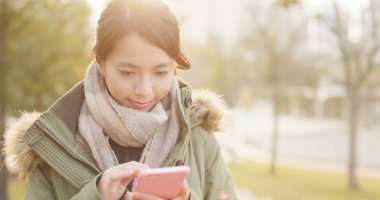 Günbatımı zamanı altında cep telefonu kullanan kadın 