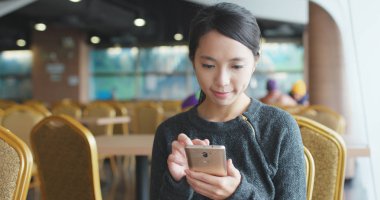 Kafede akıllı telefon kullanan bir kadın. 