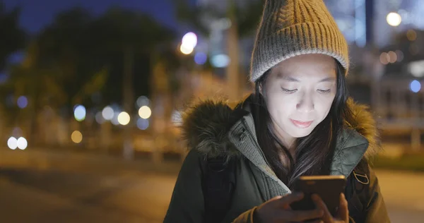 女性の冬のジャケットを着て 夜携帯電話を使う — ストック写真