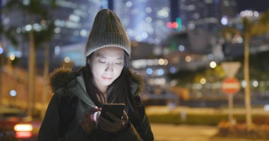 Asyalı kadın Smartphone şehirde geceleri kullanarak. 