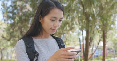 Parkta cep telefonu kullanan bir kadın. 