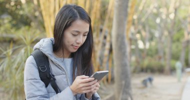 Parkta cep telefonu kullanan bir kadın. 