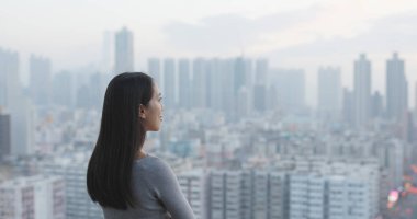 Kadın şehir manzarasına bakıyor. 