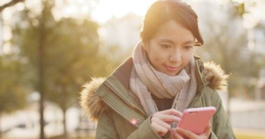 Günbatımı zamanı altında cep telefonu kullanan kadın 