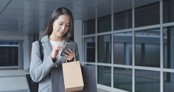 Kobieta Przy Użyciu Telefonu Komórkowego Przytrzymując Torby Zakupy — Zdjęcie stockowe