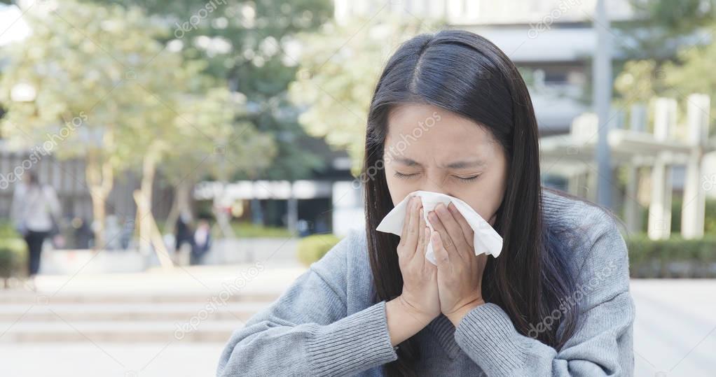 Asian Woman sneezing at outdoor 