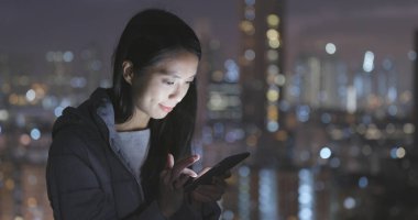 Geceleri şehri cep telefonu kullanan kadın 