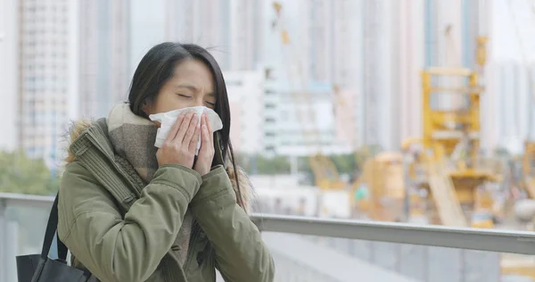 妇女在室外打喷嚏在建筑现场背景 — 图库照片