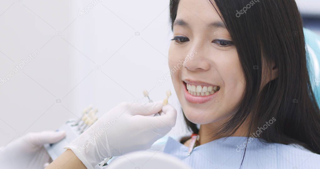 Woman compare the color of tooth sample 