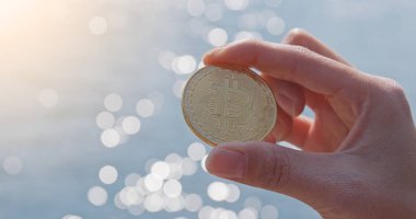 Bitcoin deniz manzarası arka plan üzerinde tutan kadın 