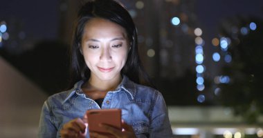 Hareket eden telefon içinde cityscape geceleri kullanan kadın 