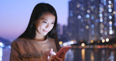 Gece şehirde akıllı telefon kullanan bir kadın. 