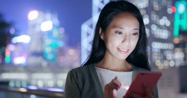 Geceleri cep telefonu kullanan genç bir kadın. 