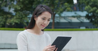 Şehirde tablet bilgisayar kullanan bir kadın. 