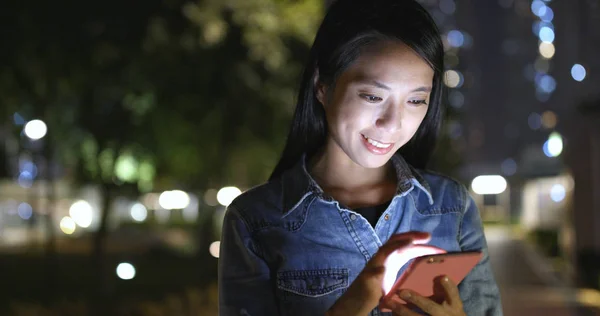 夜间在城市景观中使用手机的妇女 — 图库照片