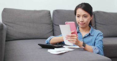 Alış irsaliyesindeki fotoğraf çekmek ve günlük yaşam harcama hesaplamak için cep telefonu kullanarak ev kadını 