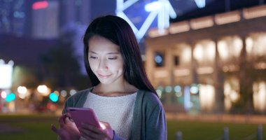 Geceleri cep telefonu kullanan bir kadın. 