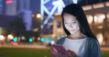 Geceleri cep telefonu kullanan bir kadın. 