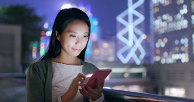 Geceleri cep telefonu kullanan genç bir kadın. 