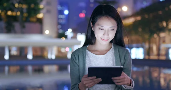 Woman looking at tablet computer in city at night