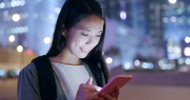 Geceleri akıllı telefon kullanan Asyalı bir kadın. 