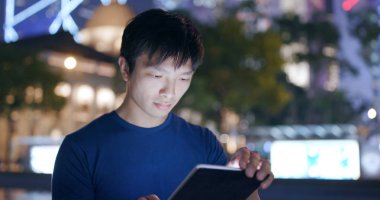 Genç adam smartphone şehirde geceleri kullanarak. 