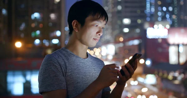 Asian man using mobile phone in city at night