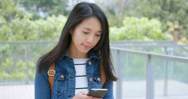 Cep telefonu kullaranarak ve sokakta yürürken genç kadın 