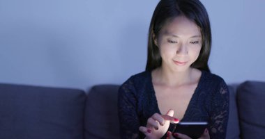 Evde cep telefonu kullanan bir kadın 