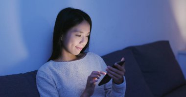 Geceleri cep telefonu kullanan bir kadın. 