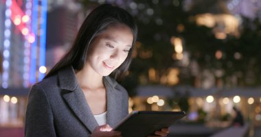 Genç işkadını geceleri tablet bilgisayar kullanarak 