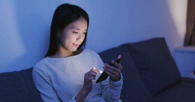 Akşamları evde cep telefonu üzerinde çalışan kadın 