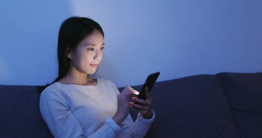 Akşamları evde cep telefonu üzerinde çalışan kadın 