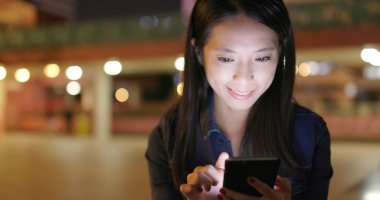 Geceleri cep telefonu kullanan bir kadın. 