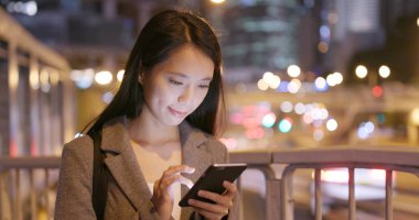 İşkadını bak smartphone vasıl trafik yol arka plan üzerinde 