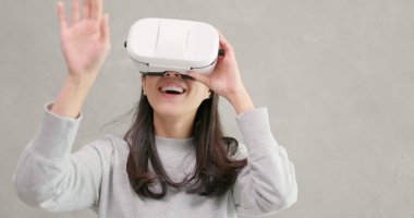 VR aygıt gri arka plan üzerinde oynayan kadın 