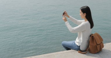 Deniz manzarası ile cep telefonu üzerinde fotoğrafta kadın 