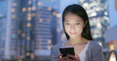 Kadın geceleri cep telefonuyla çalışıyor. 