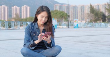 Şehirde cep telefonu kullanan genç bir kadın. 