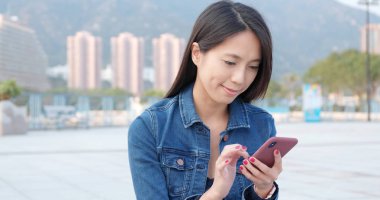 Asyalı kadın şehirde smartphone kullanarak 