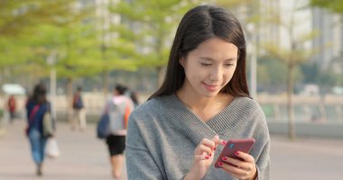 Günbatımı altında cep telefonu kullanan kadın 