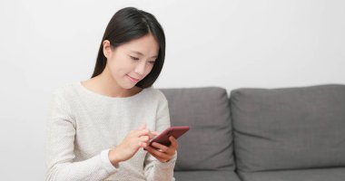 Evde cep telefonu kullanan bir kadın 