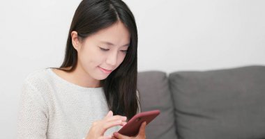 Evde cep telefonu kullanan bir kadın 