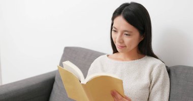 Kadın evde kitap okuyor. 