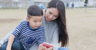 Anne ve oğlu Şehir Parkı içinde hareket eden telefon ile sohbet