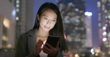 Geceleri cep telefonu kullanan genç iş kadını 