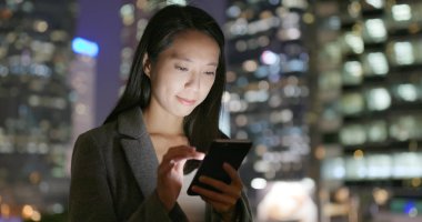 Geceleri cep telefonu kullanan genç iş kadını 