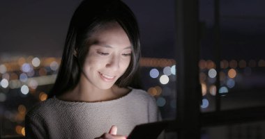 Evde cep telefonu kullanan bir kadın 