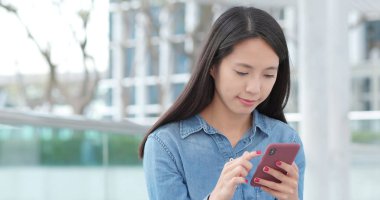 Şehirde cep telefonu kullanan genç bir kadın. 